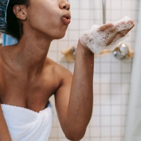 woman in towel blowing bubbles